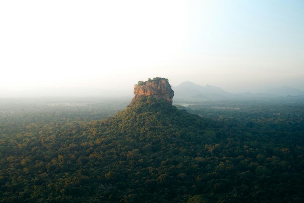 Sunrise view of Sigiriya Rock fortress from the summit of Pidurangala Rock with misty valleys below