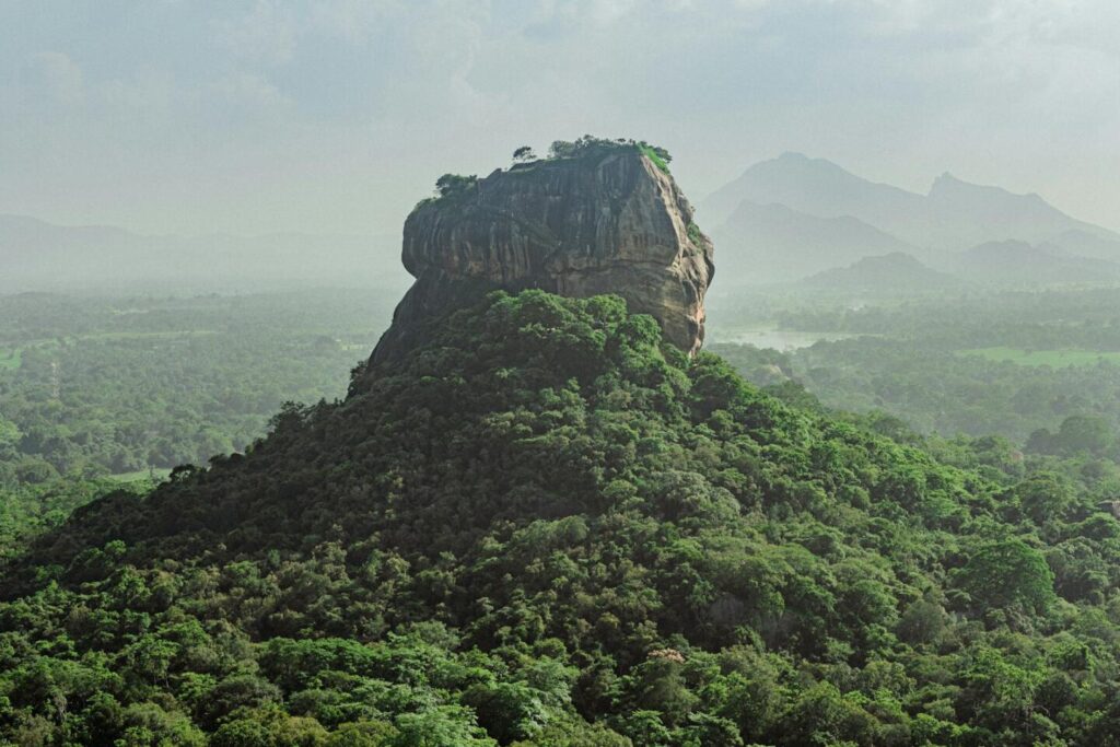 Sunset view of Sigiriya Rock from Pidurangala Rock with lush greenery surrounding — supporting travel image 3