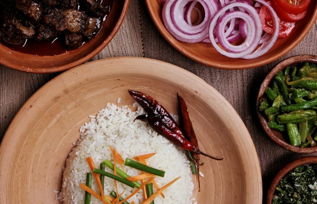 A colorful plate of Sri Lankan rice and curry with various vegetable and meat curries alongside traditional condiments — supporting travel image 3