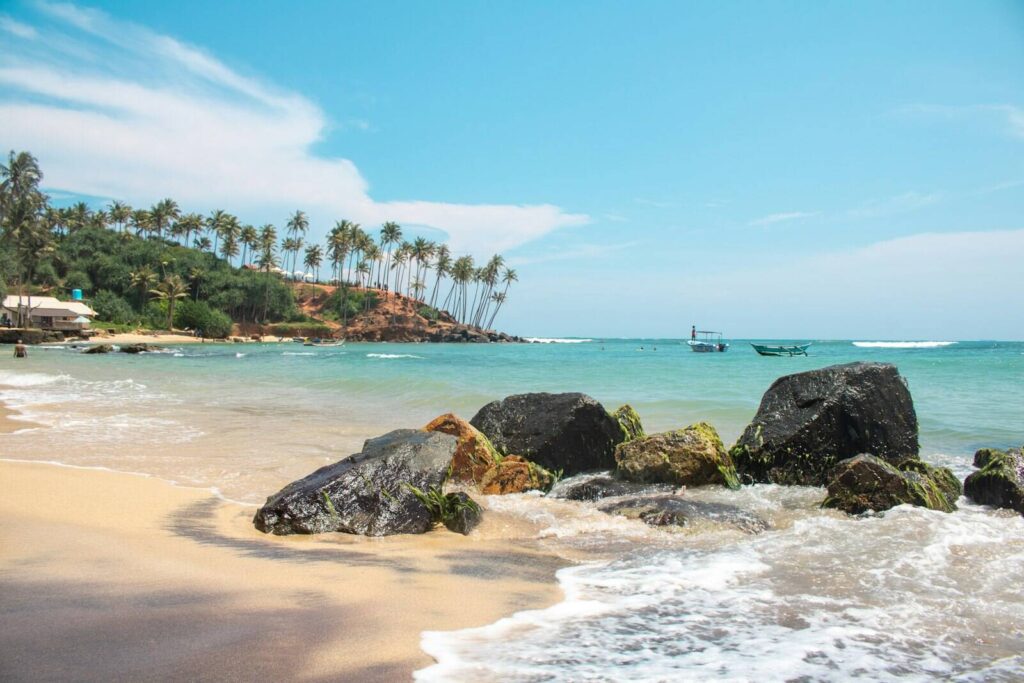 View of golden sandy beach in Sri Lanka with palm trees and clear blue water