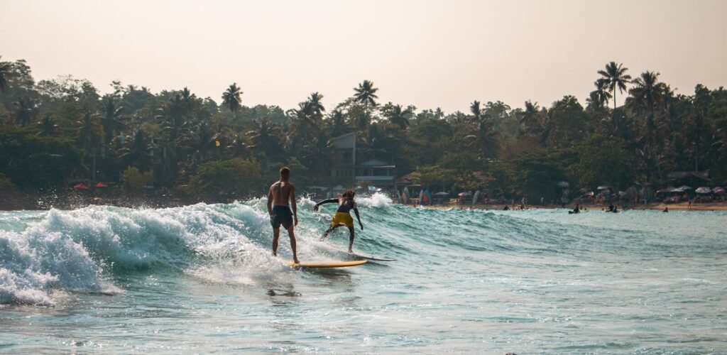Surfer riding a wave on a sunny day at a palm-lined beach in Sri Lanka — supporting travel image 2