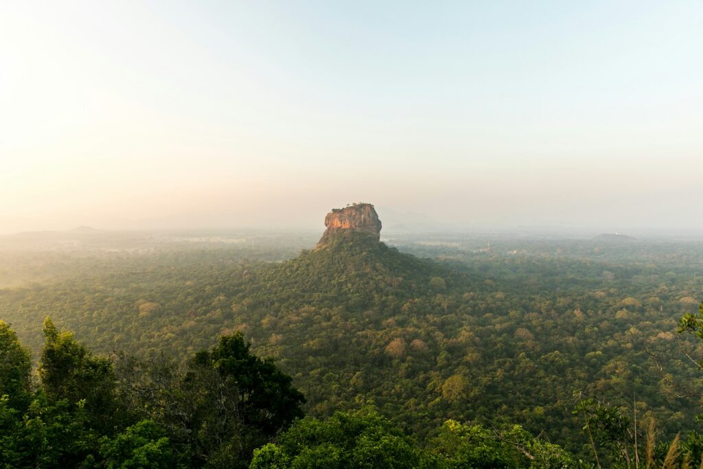 View of Sigiriya Lion Rock fortress rising above the lush Sri Lankan landscape at sunrise — supporting travel image 3